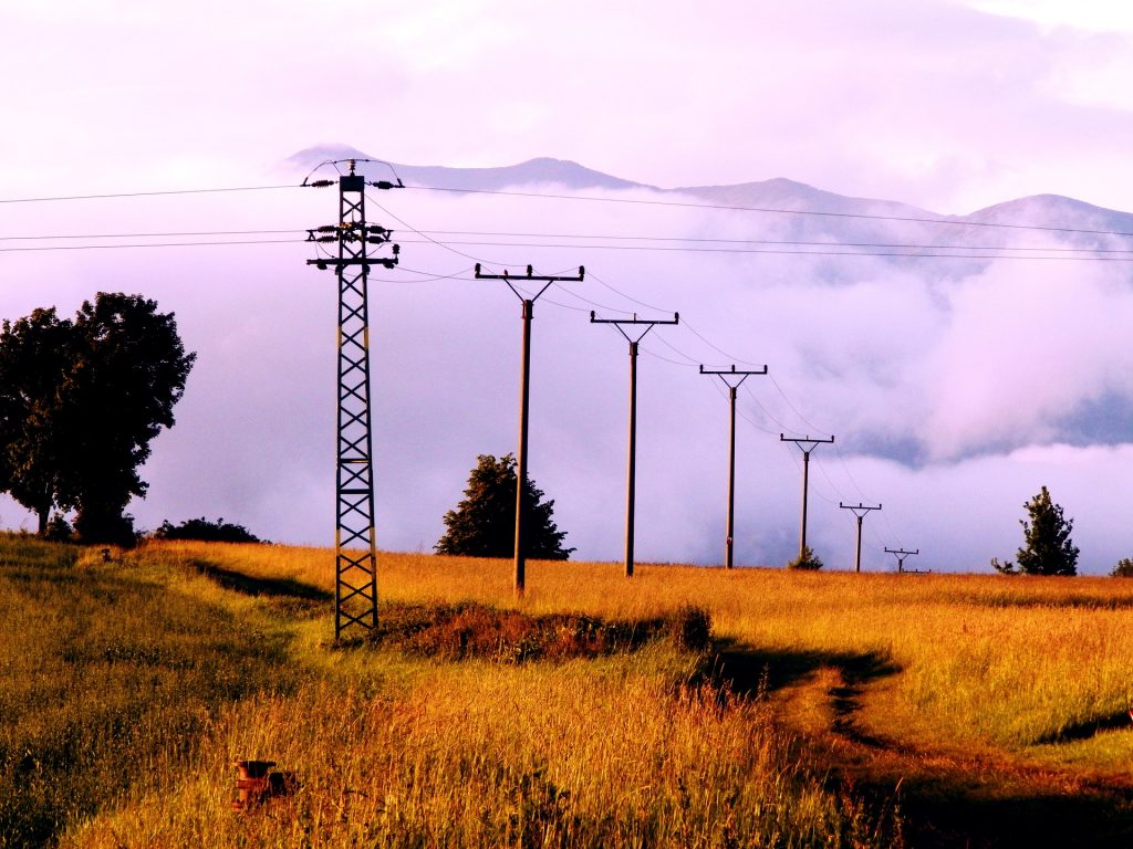 A picture showing electrical pylons spreading out across an open field, a reminder of the need for safely grounding electricity