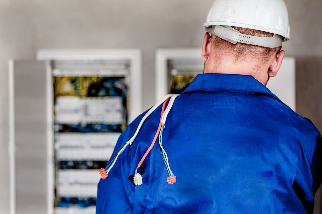 A picture showing a man in a blue shirt and hard hat, part of a blog post on choosing your electrician