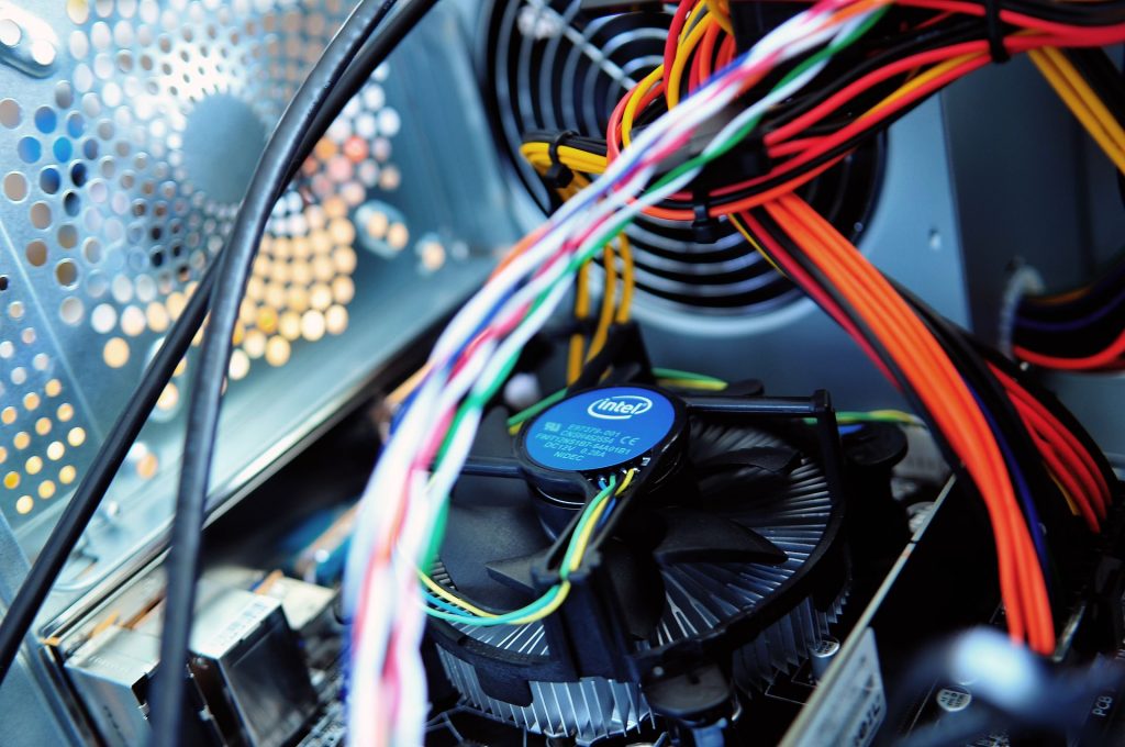 A picture showing wires and a fan inside of a computer, parts of equipment that are checked in electrical testing