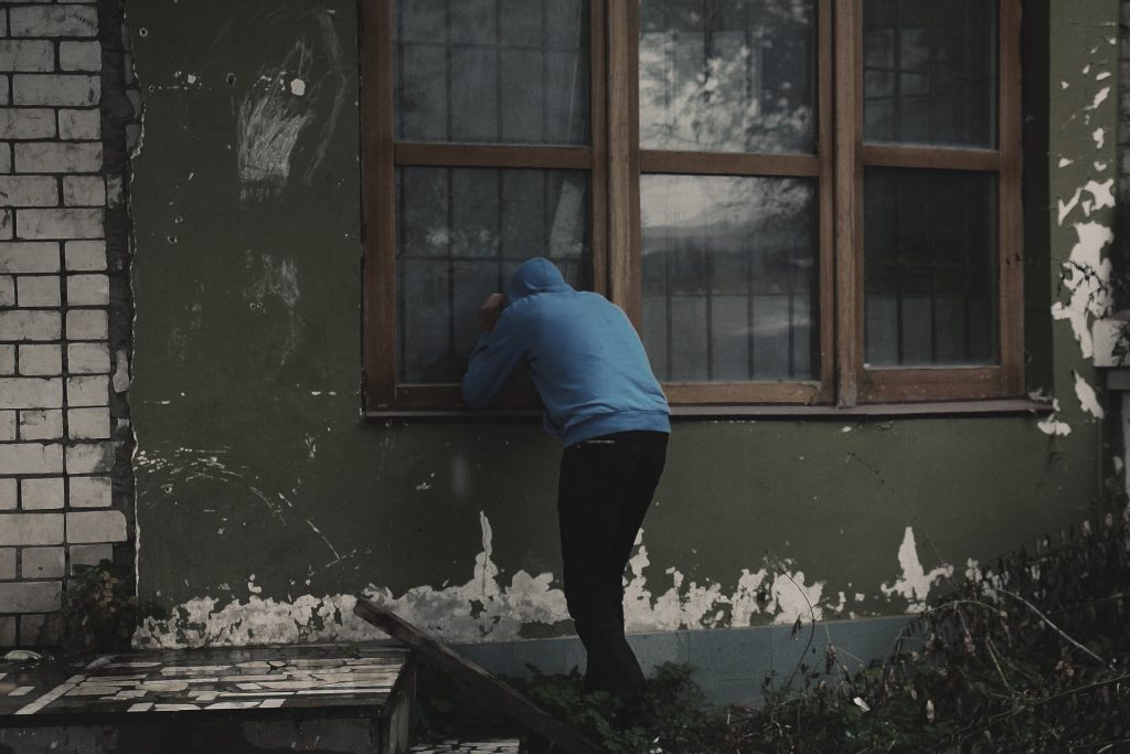 A picture of burglar looking into a house without an intruder alarm or home security