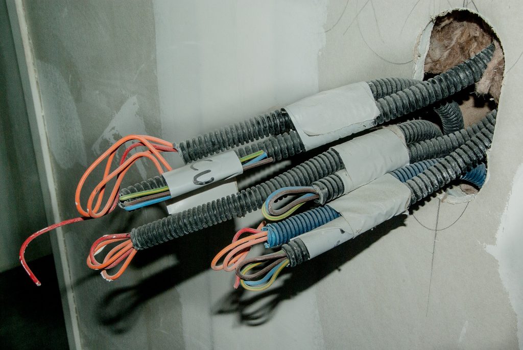 A picture of wires coming out of a wall, part of a routine inspection done for electrical test certificates