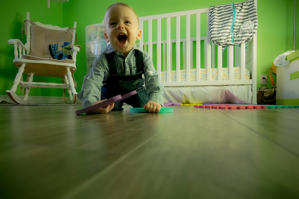 A picture of a toddler in his playroom, one of the places that you should remember when baby proofing your home against the risk of electric shock